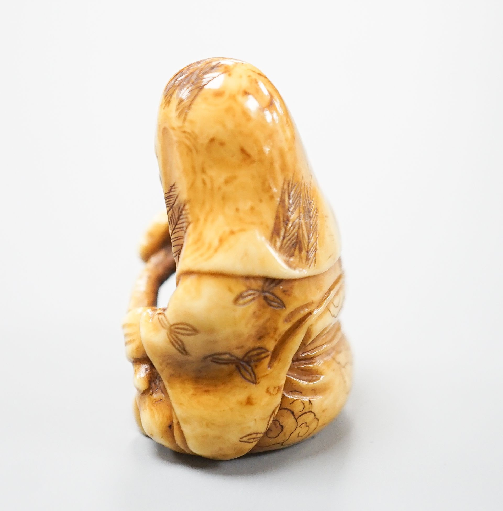 A Japanese ivory netsuke of Fukurokuju seated, holding a sceptre, early 20th century, 3.8cm